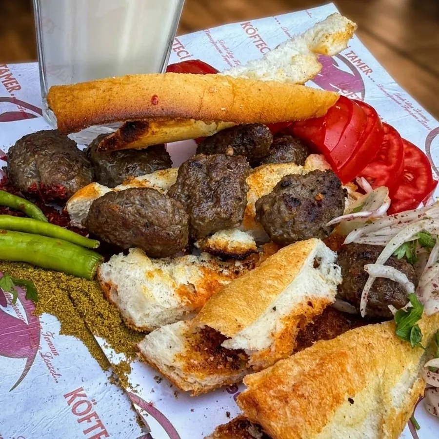 Kâğıt üzerinde köfte, közlenmiş ekmek, domates ve ayran